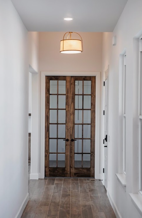Hallway with stained french doors and crisp white walls
